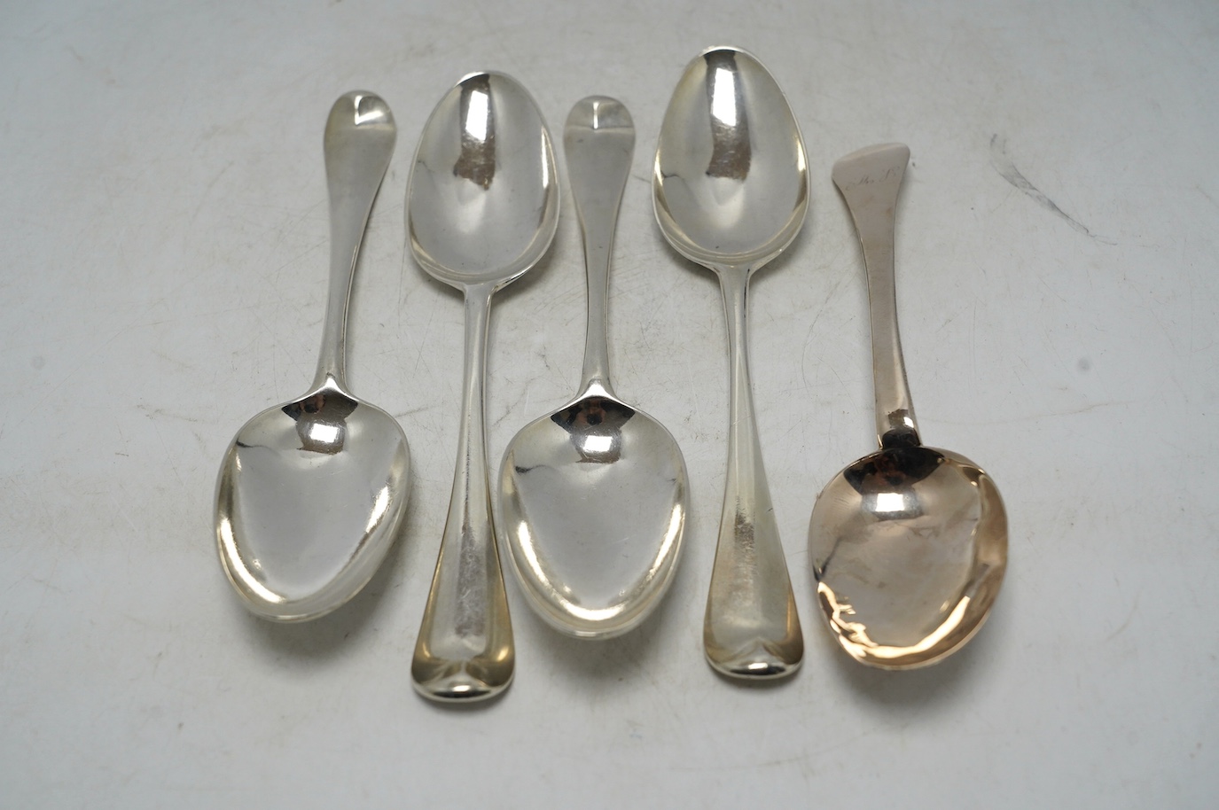 An early 18th century? silver dog nose spoon, indistinct marks, 19.2cm, together with a set of four George II silver table spoons, with lace back bowls, by William Turner, London, 1755, 10.6oz. Condition - poor to fair